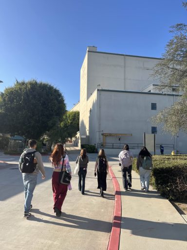 Group of people walking towards a building under a clear blue sky.