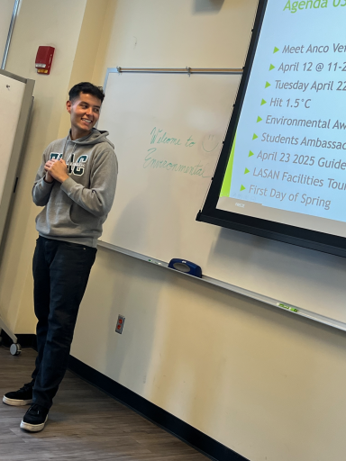 A happy person standing in front of a presentation screen in a classroom setting.